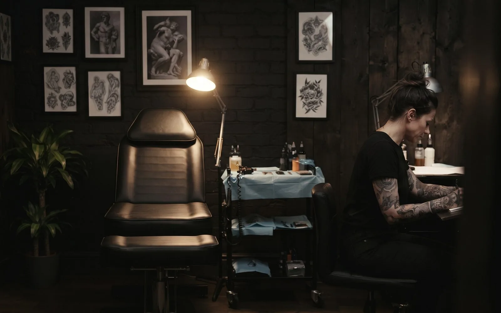Blick in das dunkle Atelier mit Tätowierstuhl unter einer Arbeitsleuchte